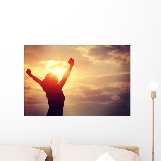cheering woman open arms at sunrise seaside Wall Mural