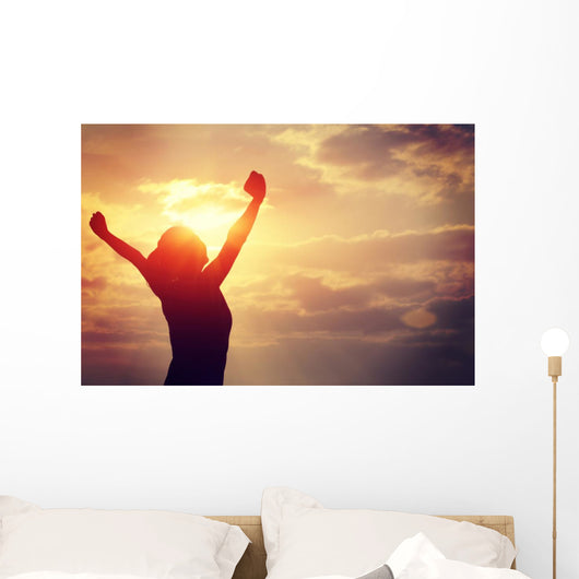 cheering woman open arms at sunrise seaside Wall Mural