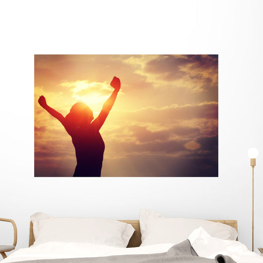 cheering woman open arms at sunrise seaside Wall Mural
