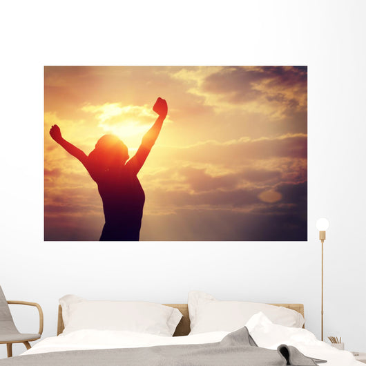 cheering woman open arms at sunrise seaside Wall Mural