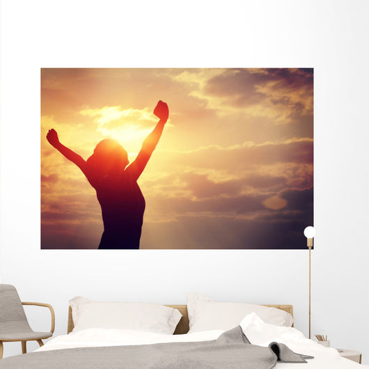 cheering woman open arms at sunrise seaside Wall Mural