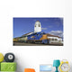 Train engine pulls its cars by the depot with blue sky Wall Mural