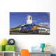 Train engine pulls its cars by the depot with blue sky Wall Mural