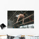 Athlete topless doing exercises on the uneven bars Wall Mural