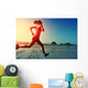 young woman running on sunrise beach  Wall Mural