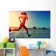 young woman running on sunrise beach  Wall Mural