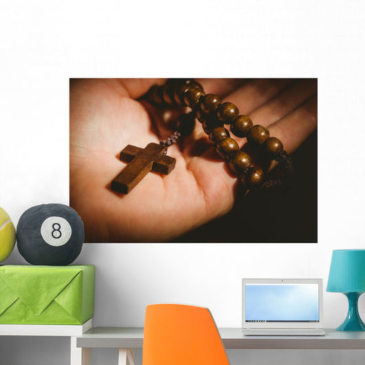Hand holding wooden rosary beads Wall Mural