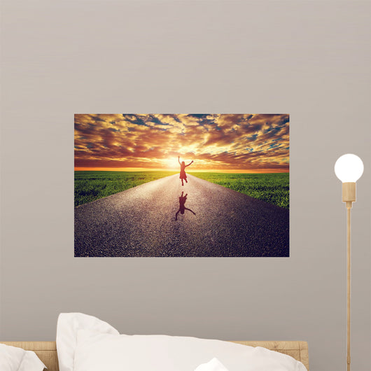 Happy woman jumping on long straight road, way towards sun Wall Mural