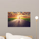 Happy woman jumping on long straight road, way towards sun Wall Mural