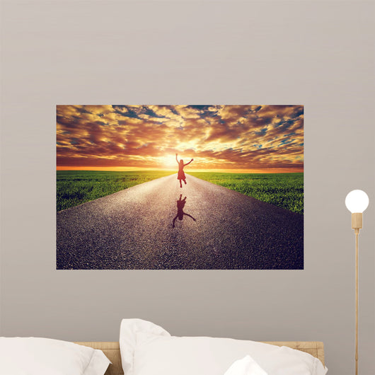 Happy woman jumping on long straight road, way towards sun Wall Mural