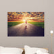 Happy woman jumping on long straight road, way towards sun Wall Mural