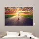Happy woman jumping on long straight road, way towards sun Wall Mural