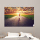 Happy woman jumping on long straight road, way towards sun Wall Mural