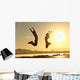 Fitness couple jumping happy at sunset Wall Mural