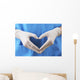 Doctor showing shape of heart by his hands in sterile gloves, Wall Mural