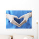 Doctor showing shape of heart by his hands in sterile gloves, Wall Mural