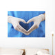 Doctor showing shape of heart by his hands in sterile gloves, Wall Mural
