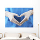 Doctor showing shape of heart by his hands in sterile gloves, Wall Mural