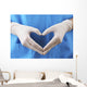 Doctor showing shape of heart by his hands in sterile gloves, Wall Mural