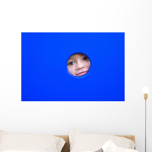 little kid playing peek-a-boo on a playground Wall Mural