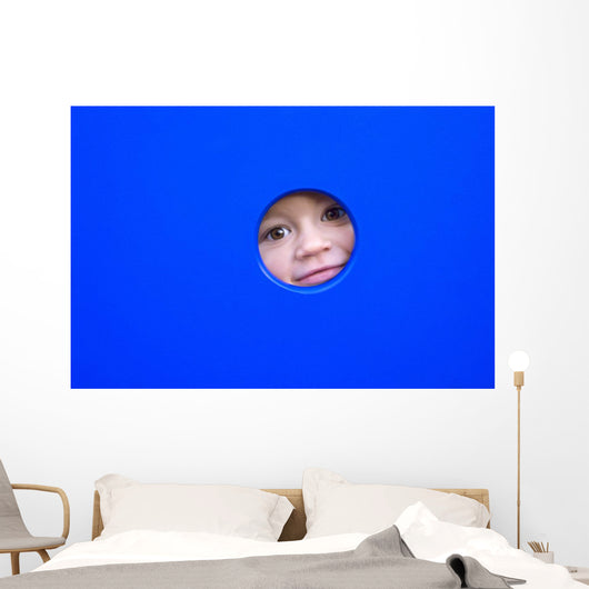 little kid playing peek-a-boo on a playground Wall Mural