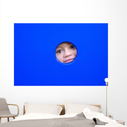 little kid playing peek-a-boo on a playground Wall Mural