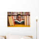 Cute boy reading book in library Wall Mural