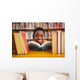 Cute boy reading book in library Wall Mural