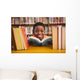 Cute boy reading book in library Wall Mural