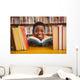 Cute boy reading book in library Wall Mural