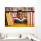 Cute boy reading book in library Wall Mural
