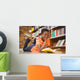 Cute boy reading book in library Wall Mural