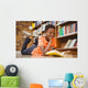 Cute boy reading book in library Wall Mural