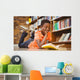 Cute boy reading book in library Wall Mural