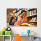 Cute boy reading book in library Wall Mural