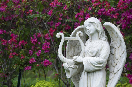 White marble statue of angel in flower garden Wall Mural
