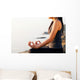 The woman meditating in a yoga pose on the tropical beach. Wall Mural