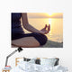 The woman meditating in a yoga pose on the tropical beach. Wall Mural
